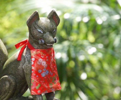 Statue of Inari fox holding a scroll in its mouth