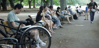Yoyogi Park in Tokyo, People taking a break on benches under the trees