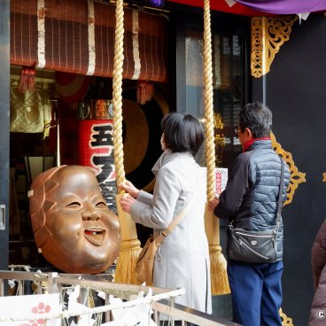 Asakusa Otori-jinja (Tokyo), Visitors praying in front of the mask of the goddess Okame