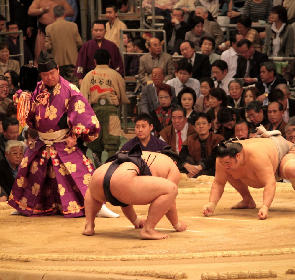 Sumo tournament in Osaka, Wrestlers and referee on the dohyo ring before the bout Sumo tournament in Osaka, Wrestlers and referee on the dohyo ring before the bout